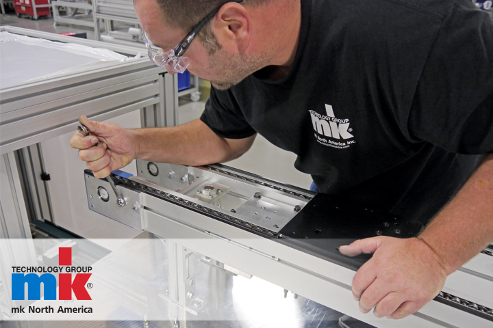 A man performing routine maintenance on a conveyor system.